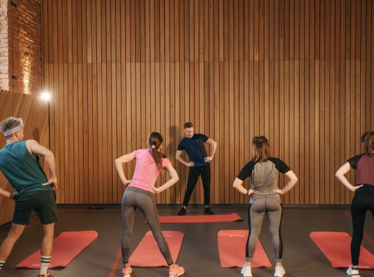 People stretching on yoga mats during a fitness class indoors.