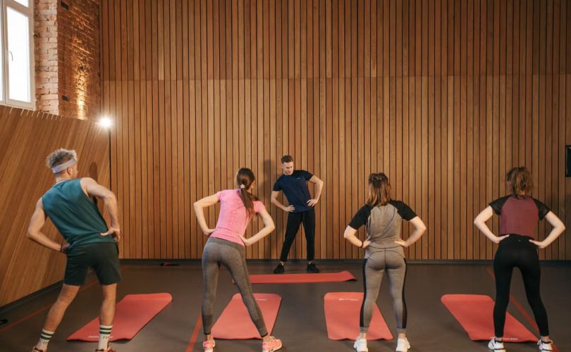 People stretching on yoga mats during a fitness class indoors.